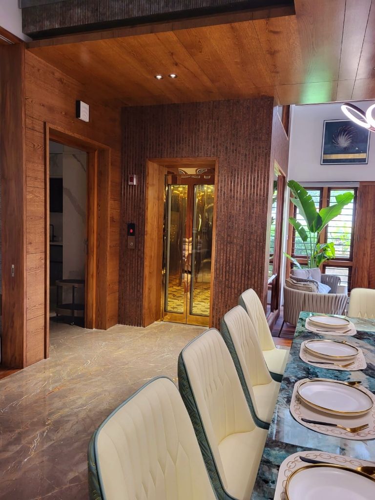 Gold-framed lift doors in a teak-panelled dining hall with a marble floor