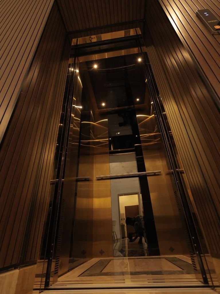 Lift cabin with glass doors and dark wood-grain walls