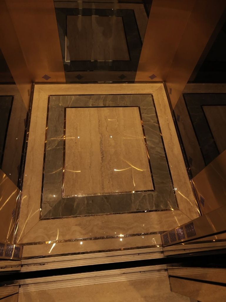 Marble and stone inlay floor of a lift cabin framed in gold