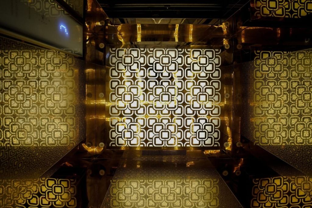 Gold cut-work cabin walls and a lit patterned ceiling seen from above